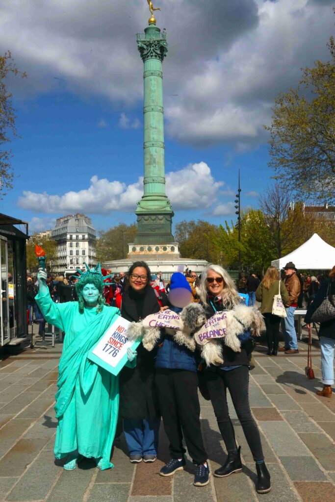 photo shows protestors signs in front of bastille column at No Kings 3 on March 28th 2026 in Paris France